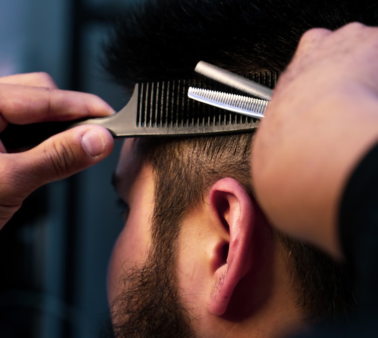 A barber combing and cutting hair at the nape